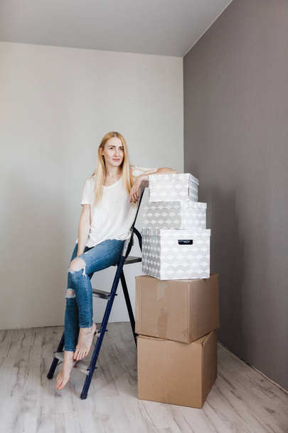 mortgage, people and real estate concept - happy woman with boxes moving to new home - Photo, image
