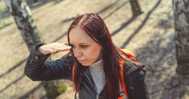 Traveling woman with backpack in woods Side view of brunette standing with bright orange backpack in tranquil sunny forest looking away - Fotó, kép