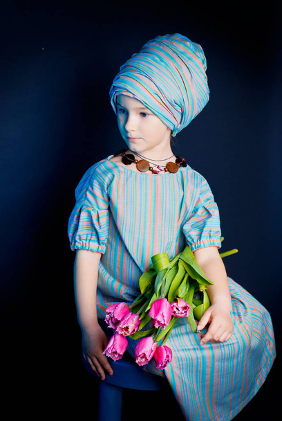 A szép lány a keleties ruhát. Édes lány egy hosszú ruhát, és a fejét egy csokor virágot a kezében a turbán - Fotó, kép
