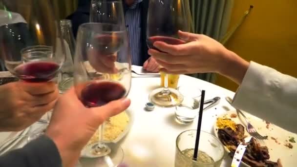 τέσσερα χέρια κρατούν κόκκινο κρασί και επευφημίες - Πλάνα, βίντεο