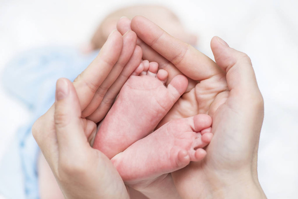 母の手に赤ちゃんの足。ママと子供ハッピーファミリーコンセプト。マタニティの美しい概念イメージ。母は生まれたばかりの赤ん坊の素足を保持する - 写真・画像