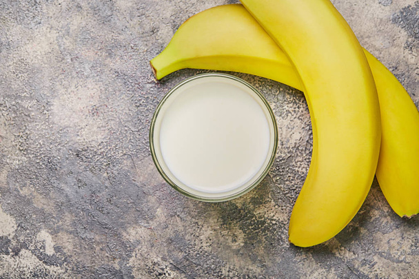 Glass milk with banana on gray background. Top view. - Фото, зображення