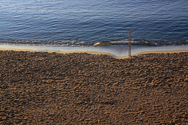Άνθρωποι ποδοπατούνται άμμο στην παραλία στη Μεσόγειο θάλασσα  - Φωτογραφία, εικόνα