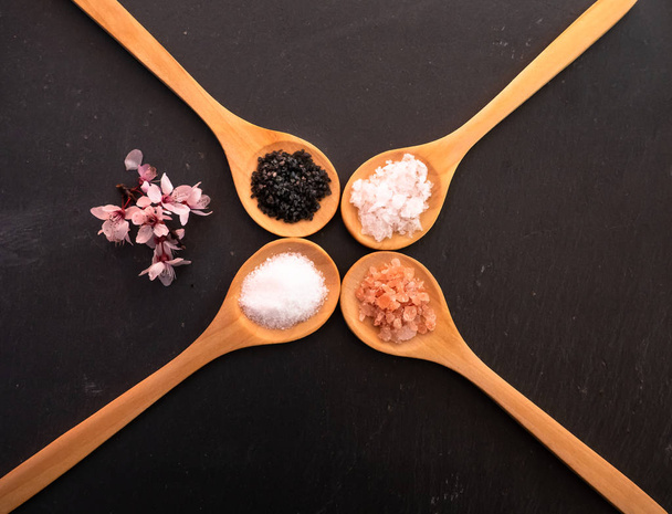 Drewniane łyżki z solą himalajską, czarną solą hawajską, solą zwyczajną i płatkami soli na talerzu łupkowym - Zdjęcie, obraz