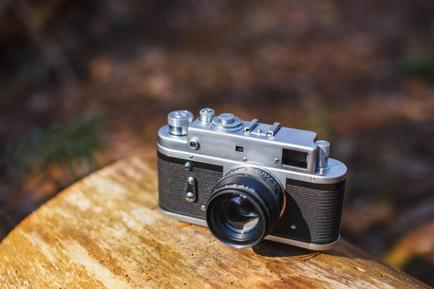 Old retro film camera in a sunny spring forest - Foto, afbeelding
