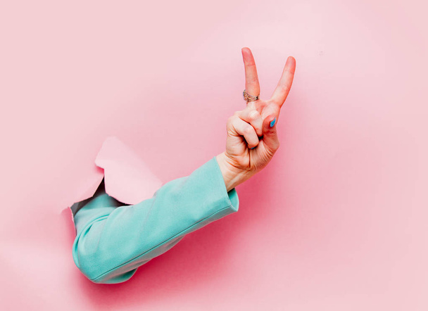 Женская рука в классической голубой куртке шоу ОК символ смотрит из розового фона
 - Фото, изображение