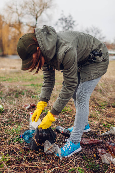 Woman volunteer cleaning up the trash in park. Picking up litter outdoors. Ecology and environment concept - Фото, изображение