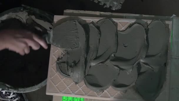 Руки шпателем наносять клеєм бетон на поверхню плитки стіни
 - Кадри, відео