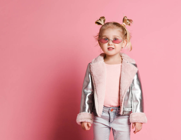 Portrait of a little girl in stylish clothing posing on pink background and playing up - Fotó, kép