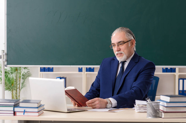 Leeftijd mannelijke leraar in de voorkant van schoolbord  - Foto, afbeelding