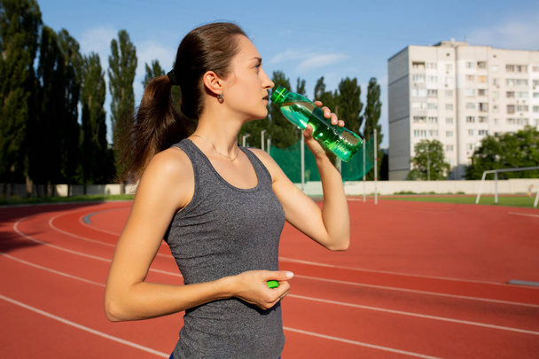 Impressionante bruna donna che beve acqua durante la corsa allo stad
 - Foto, immagini