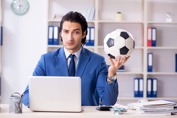 junger gutaussehender Geschäftsmann mit Fußball im Büro  - Foto, Bild