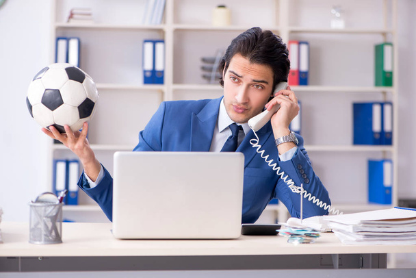 Joven hombre de negocios guapo con pelota de fútbol en la oficina
  - Foto, Imagen