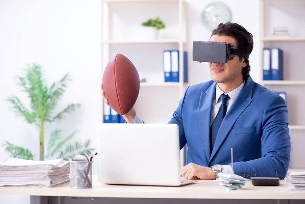 Молодой привлекательный бизнесмен играет в регби с виртуальными очками
 - Фото, изображение
