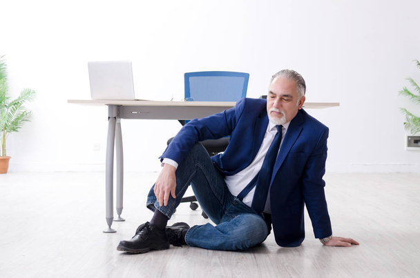 Aged businessman doing yoga exercises in the office  - Фото, зображення