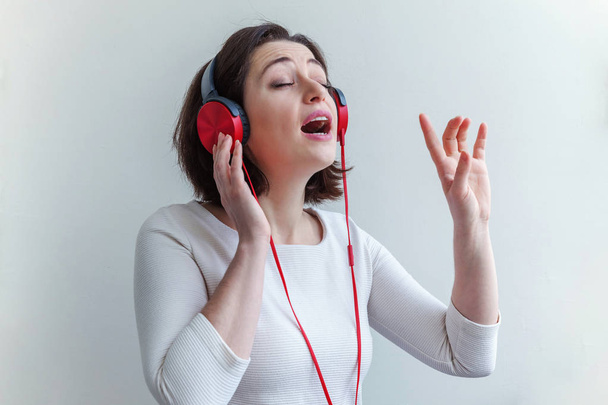 Enerji genç esmer Bayan kadın dinleme müzik kulaklık ve beyaz arka plan üzerinde izole şarkı - Fotoğraf, Görsel
