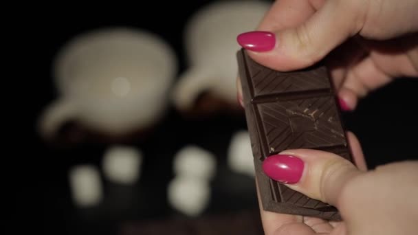 Nainen rikkoo mustan suklaapatukan. Lähemmäs. Hidastus
 - Materiaali, video