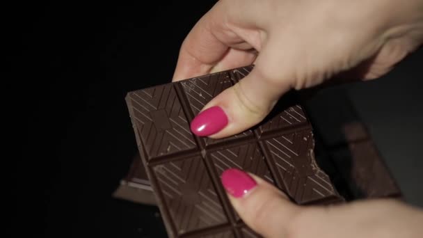 Vrouw einden zwarte chocolade bar. Close-up. Slow motion - Video