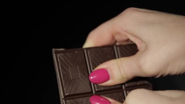 Nő szünetek fekete csokoládé. Közelről. Lassú mozgás - Felvétel, videó