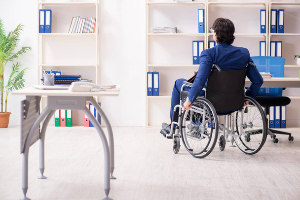 Nuori miespuolinen pyörätuolissa työskentelevä työntekijä työskentelee toimistossa  - Valokuva, kuva