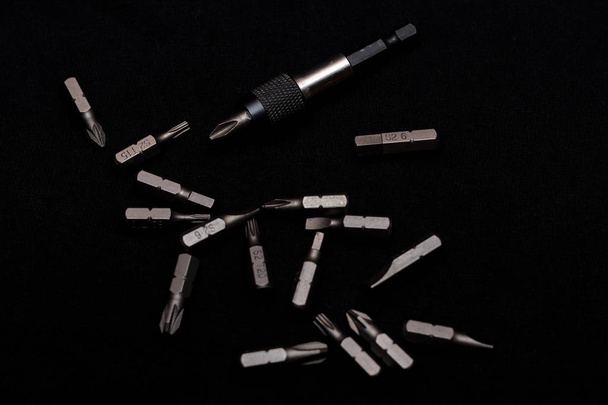 Herramienta de bits de acero al carbono con soporte de bits sobre fondo negro en estilo clave oscura.  - Foto, Imagen