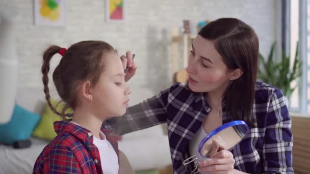 Close up mom teaches daughter to use cosmetics - Felvétel, videó