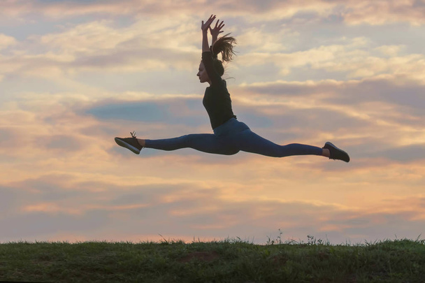 Спортивна молода жінка стрибає на фоні ранкових хмар, в
 - Фото, зображення
