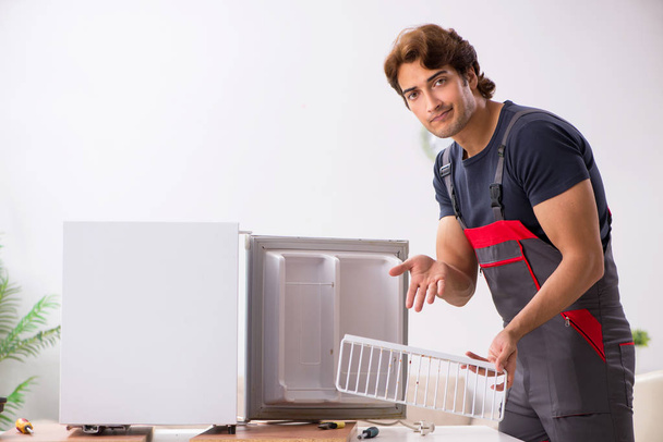 Jonge knappe aannemer herstellen koelkast  - Foto, afbeelding