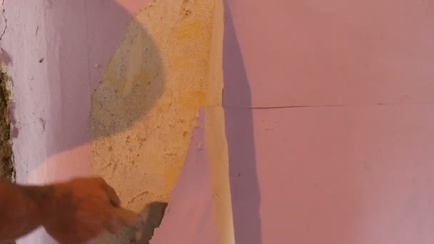 Uros rakentajat käsi repii pois tai kuori vanha vaaleanpunainen tapetti seinästä erityisellä lastalla
 - Materiaali, video