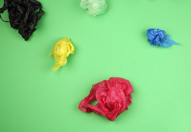 crumpled used colored plastic bags on green background, big ecol - Foto, Bild