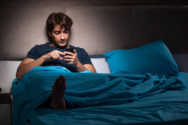 Junger Mann schreibt spät in der Nacht SMS auf Handy - Foto, Bild