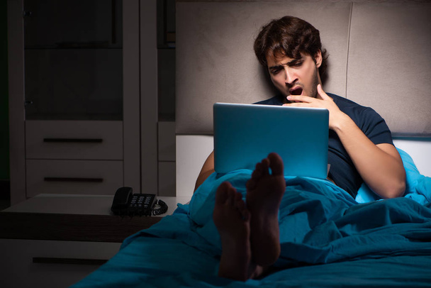 Homme travaillant sur ordinateur portable la nuit au lit
 - Photo, image