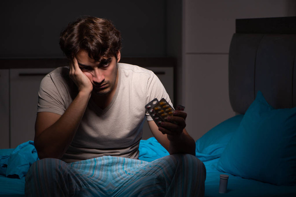 Nemocný muž v posteli s léky - Fotografie, Obrázek