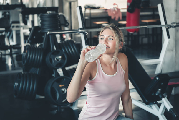 Красивая фитнес-женщина пьет воду из бутылки после работы
 - Фото, изображение