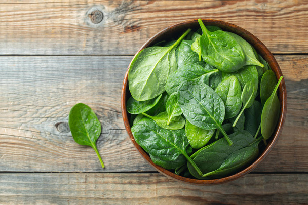 Fresh spinach leaves in bowl on wooden table. - Foto, Imagen