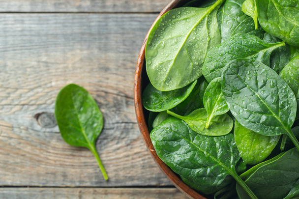 Fresh spinach leaves in bowl on wooden table. - Фото, изображение