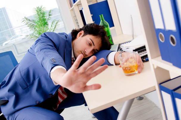 Young businessman employee drinking in the office  - Фото, изображение