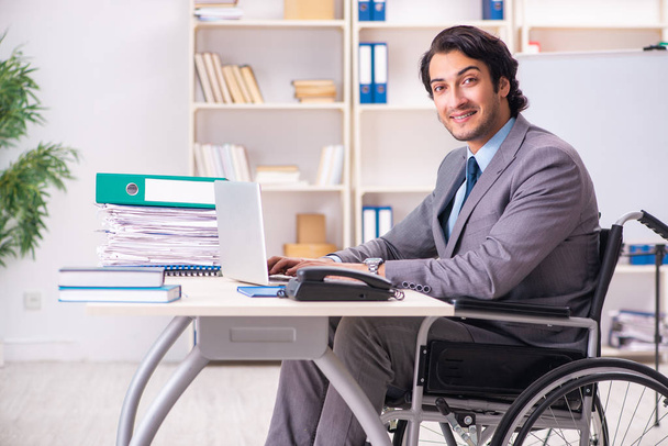 Молодий красивий працівник в інвалідному візку в офісі
  - Фото, зображення