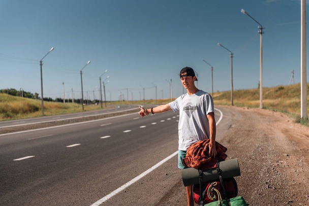 Travel man hitchhiking. Backpacker on road - 写真・画像