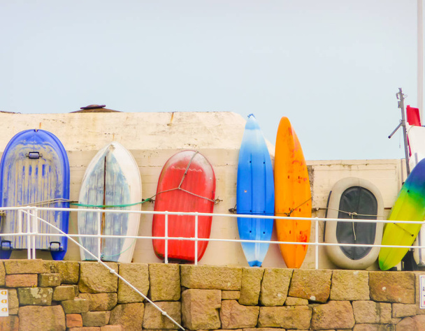 Barco Fisher e pranchas de surf alinhadas contra uma parede para secar
 - Foto, Imagem