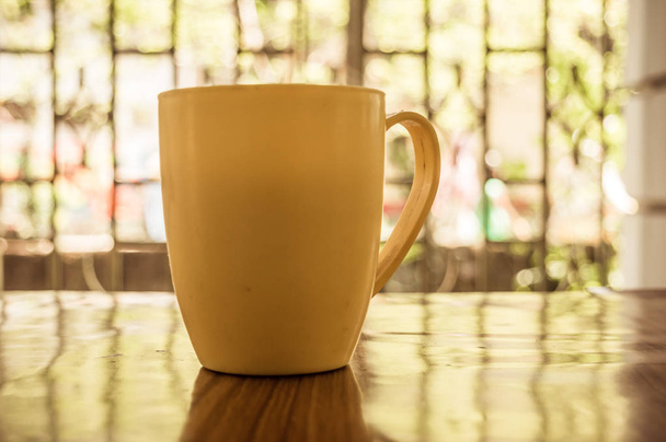 Nahaufnahme Bild einer Tasse Cappuccino, Mokka, Latte, Americana, Espresso heißes Kaffeearoma für auf rustikalem Holztischhintergrund im Café mit Hintergrund des Sonnenlichts, das morgens aus dem Fenster kommt. - Foto, Bild