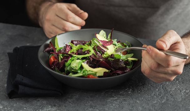 Man is eating vegetable salad. Healthy lunch or breakfast concept. Clean and balanced food - Fotó, kép