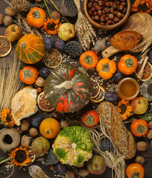 Pumpkins, persimmon, cereals, bread, seeds and nuts on a wooden background, Harvest, Autumn - Фото, изображение