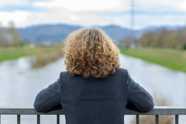 Γυναίκα με σγουρά μαλλιά που βλέπουν το ποτάμι - Φωτογραφία, εικόνα