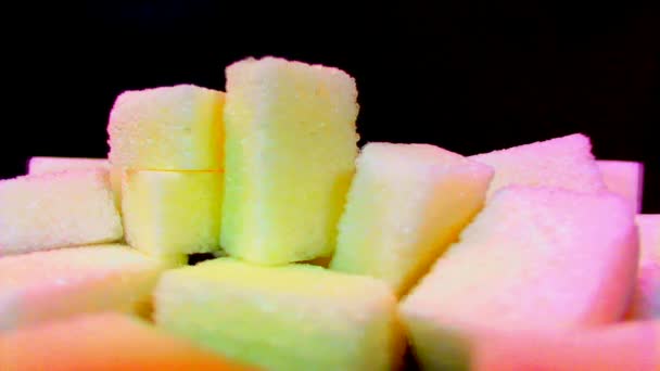 Uma pilha de pedaços de açúcar gira contra um fundo preto
 - Filmagem, Vídeo