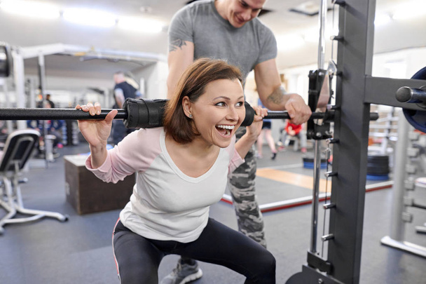 Middle-aged woman doing sports exercise in fitness center. Perso - Foto, Imagen