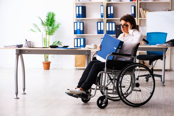 Сотрудница в инвалидной коляске в офисе   - Фото, изображение