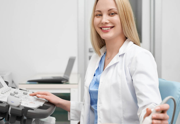 Positive female doctor in white uniform looking at camera - Zdjęcie, obraz
