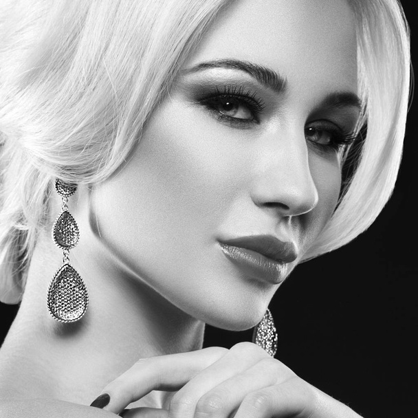 Portrait de jeune femme blonde avec accessoires tendance et maquillage élégant posant sur fond noir
 - Photo, image