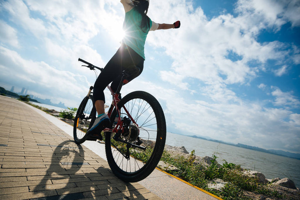 Hands free cycling woman riding Mountain Bike on sunrise seaside - Foto, imagen
